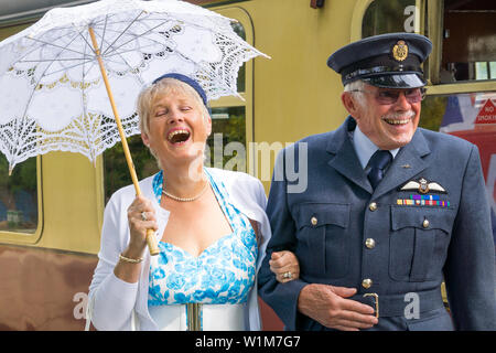 Kidderminster, Großbritannien. Juni 2019. Severn Valley Railways 'Step Back to the 40's' startet dieses Sommerwochenende mit kostümierten Re-Enactors, die ihre Rolle bei der Bereitstellung einer authentischen Erholung von Wartime Britain spielen. Ein entzückendes, glückliches Ehepaar aus den vierziger Jahren steht auf dem Bahnsteig eines alten Bahnhofs und genießt Gespräche mit Freunden, bevor sie in den wartenden Dampfzug einsteigen. Kredit: Lee Hudson Stockfoto