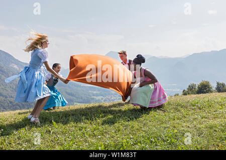 Teenage Freunde verbreiten Picknickdecke auf gras landschaft, Bayern, Deutschland Stockfoto