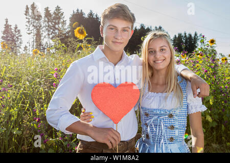 Teenage Paar vor sonnenblumenfeld, Bayern, Deutschland Stockfoto