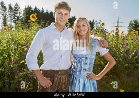 Teenage Paar vor sonnenblumenfeld, Bayern, Deutschland Stockfoto