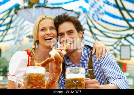 Paar mit Bier und Brezel in einem Bierzelt Stockfoto