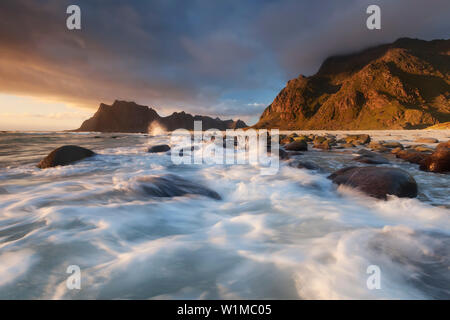 Sonnenuntergang über den Lofoten Insel Vestvågøy mit Blick auf den Strand von Utakleiv mit Wellen im Vordergrund, Norwegen, Skandinavien Stockfoto