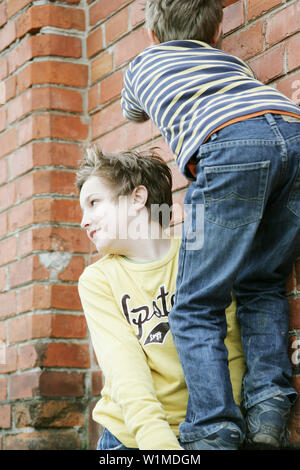 Zwei jungen, die über eine Mauer klettern Stockfoto