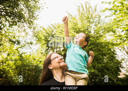Vater mit Sohn als Superheld im Garten Stockfoto