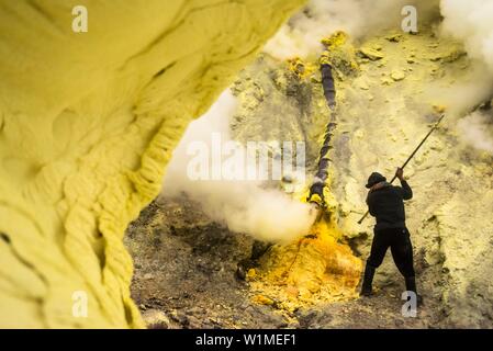 Minerworker zu giftiges Schwefeldioxid Gas der Mine ausgesetzt (Devil's mine) im Inneren des Vulkans Ijen auf der Insel Java und mit Hilfe eines Brecheisens für die s Stockfoto