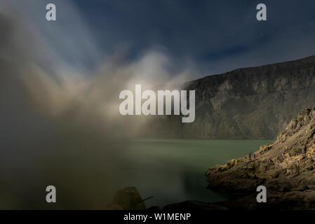 Blau säure See mit Schwefel Gase des aktiven Vulkans Ijen in der Nacht. Vollmond leuchtet, den See und die Umgebung, Ost Java, Ijen Vulkan Stockfoto