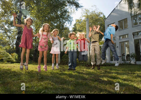 Kinder halten sich an den Händen und Springen, Kinder Geburtstag Stockfoto