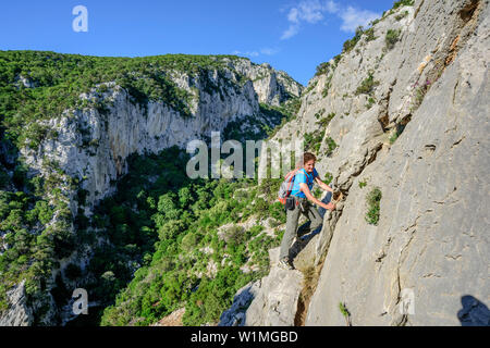 Frau Klettern über Felsen, Selvaggio Blu, National Park in der Bucht von Orosei und Gennargentu, Sardinien, Italien Stockfoto