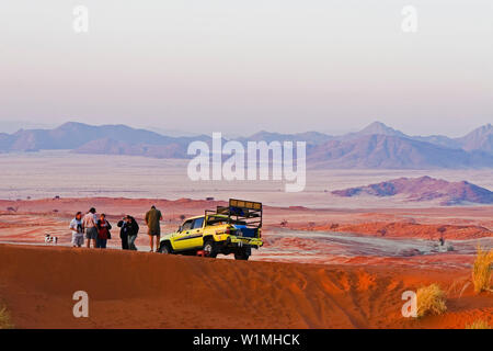 Eine Gruppe von Menschen und Auto mitten in der Wüste, kurz vor Sonnenuntergang. Gondwana Namib Desert Park. Namib Wüste. Im südlichen Namibia, Afrika. Stockfoto