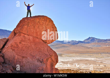 Junge Frau auf einem Felsen mit Blick auf den Sonnenuntergang, geysir Feld El Tatio, Atacama-wüste, National Reserve, Reserva Nacional Los Flamencos, Region de Antofa Stockfoto