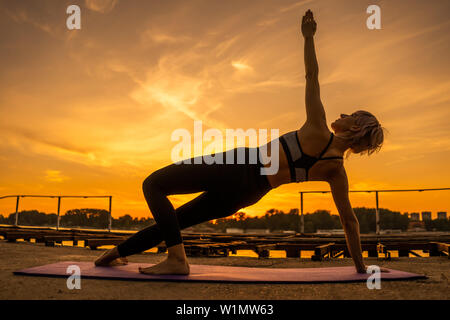 Frau Training Pilates in den Sonnenuntergang. Seitlicher Ganzkörperstütz Übung. Stockfoto