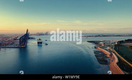 Zwei Schlepper Hirten ein Containerschiff von der Hafenmauer in Felixstowe Containerhafen, Suffolk, England. Stockfoto