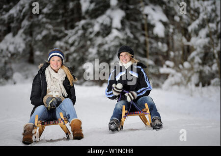 Zwei junge Frauen auf einer Schlittenfahrt, Tal der Leitzachtal, Oberbayern, Bayern, Deutschland, Europa Stockfoto