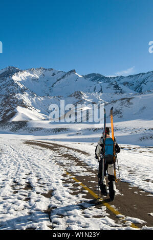 Skifahrer entlang eine verschneite Straße, Berge im Hintergrund, Las Lenas, Mendoza, Cuyo, Argentinien Stockfoto