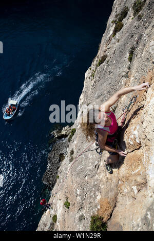 Eine junge Frau und ein junger Mann, Klettern auf den Felsen an der Bucht von Zurrieq, Malta, Europa Stockfoto