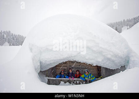 Vier Skifahrer vor einer verschneiten Hütte, Corvara, Südtirol, Italien Stockfoto
