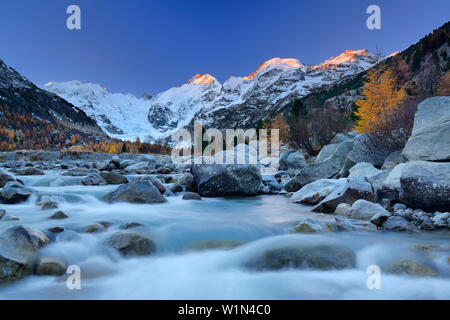 Fluss durch Morteratsch Tal im Morgenlicht mit Bernina Strecke im Hintergrund fließt, Bernina, Engadin, Graubünden, Schweiz Stockfoto