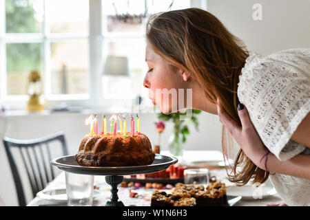 Junges Mädchen bläst die Kerzen auf der Geburtstagstorte bei Party in Hamburg, Deutschland Stockfoto
