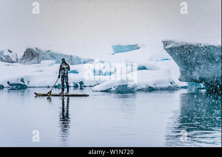 Man Stand up Paddeln auf einem Gletscher Jokulsarlon an Vatnajokul, Island Stockfoto