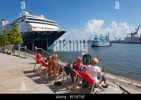 Junge Frauen sitzen auf Liegestühle an Chicagokai, Kreuzfahrtschiff Mein Schiff 1 und Raddampfer Louisiana Star im Hintergrund, Hamburg Cruise Center Stockfoto