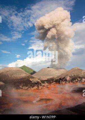 Ausbruch des aktiven Vulkan Tavurvur mit Aschewolke, dampfende - heiße Schwefelquellen in der vorderen; grüne Kegel von der "Vulcan" Vulkan in der Rückseite, Pa Stockfoto