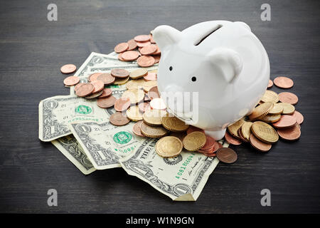Piggy Bank mit Geld auf schwarze hölzerne Hintergrund Stockfoto