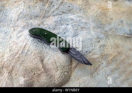 Ein Liner Lock Messer auf der Rückseite eine gebräunte Tier angezeigt ausblenden Zeigt die hübsch gestaltete Damaszenerstahl. Bokeh Wirkung. Stockfoto