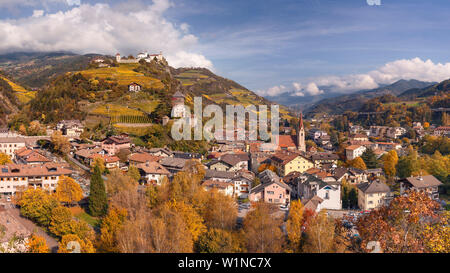 Panoramablick auf das Eisacktal über die Dächer der Stadt Klausen mit dem Schloss Branzoll und die Pfarrkirche im Herbst, Alpen, Alto Adige, Stockfoto