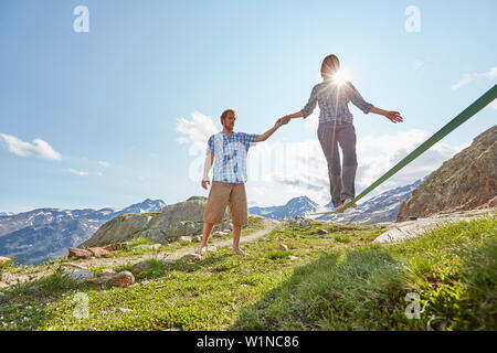 Man hilft einer Frau zu Fuß auf der Slackline Stockfoto