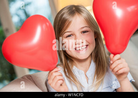 Mädchen mit zwei herzförmigen Luftballons, Hamburg, Deutschland Stockfoto