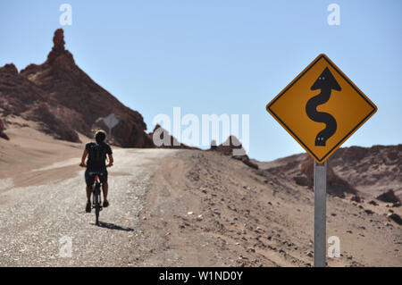 Man Radfahren und Crossing verkehrsschild an der Straße, Valle de la Luna, das Tal des Mondes, Atacama-wüste, Reserva Nacional Los Flamencos, Region de Antofag Stockfoto