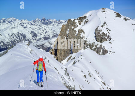 Frau back-country skiing aufsteigend auf Grat in Richtung Piz Lischana, Sesvenna Piz Lischana, Alpen, Engadin, Graubünden, Schweiz Stockfoto