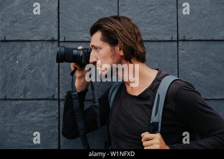 Stilvolle hipster Fotograf in einer großen Stadt mit einer Kamera und einem Rucksack auf dem Rücken. Stockfoto