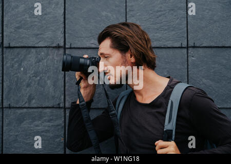 Stilvolle hipster Fotograf in einer großen Stadt mit einer Kamera und einem Rucksack auf dem Rücken. Stockfoto