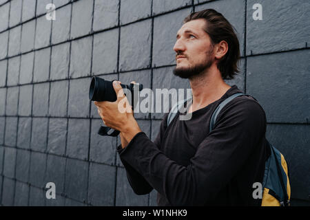 Stilvolle hipster Fotograf in einer großen Stadt mit einer Kamera und einem Rucksack auf dem Rücken. Stockfoto