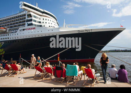 Leute sitzen auf Liegestühle an Chicagokai, vor das Kreuzfahrtschiff Queen Mary 2, Hamburg Cruise Center, Hamburg, Deutschland Stockfoto