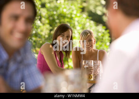 Flirten im Biergarten, zwei junge Frauen und zwei Männer flirten im Biergarten, Starnberger See, Bayern, Deutschland Stockfoto