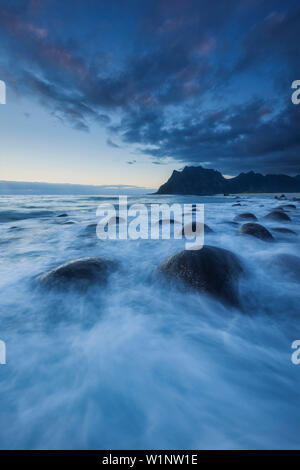 Dämmerung über der Lofoten Insel Vestvågøy mit Blick auf den Strand von Utakleiv mit Wellen im Vordergrund, Norwegen, Skandinavien Stockfoto