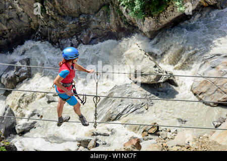 Frau klettern auf die Seilbahn auf obergurgler Klettersteig, fixed-rope Route, Fluss im Hintergrund, Obergurgler Klettersteig, Obergurgl, Ötztal, Tirol Stockfoto