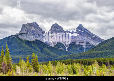 Die Canmore berühmten Three Sisters Berggipfel in der südlichen Banff Spektrum der Kanadischen Rockies an einem bewölkten Frühling Morgen. Das Trio der Peaks sind na Stockfoto