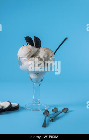 Vanilleeis mit Cookies in einem Glas closeup auf blauem Hintergrund. Stockfoto