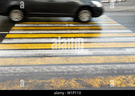 Das Auto läuft mit hoher Geschwindigkeit auf einer rutschigen Nass im Regen Fußgängerampel. Stockfoto