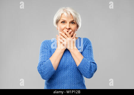 Verwirrte ältere Frau, die Ihren Mund mit der Hand Stockfoto