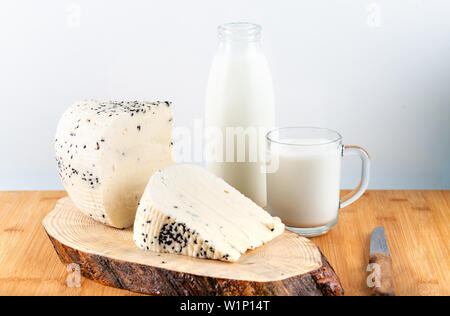 Käse mit schwarzer Kreuzkümmel mit Flasche Milch auf Holz- Hintergrund. Stockfoto