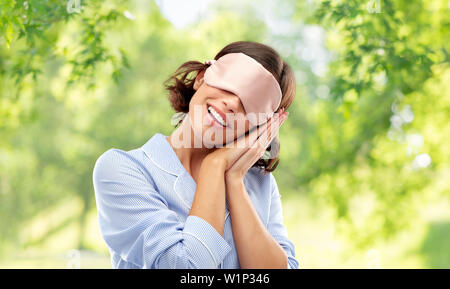 Glückliche junge Frau in Pyjama und Auge Schlafbrille Stockfoto