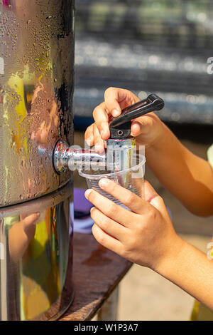 Hand junge Holding das Glas mit Wasser aus dem Kühler. Stockfoto