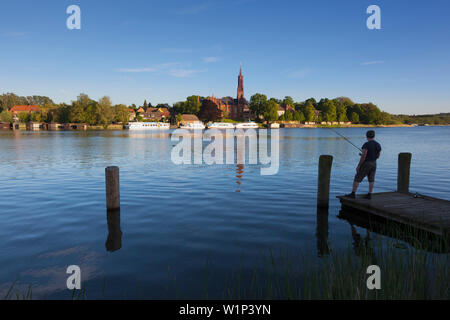 Person angeln, Blick über den See nach Malchow Kloster, Mueritz-Elde-Wasserstrasse, Mecklenburgische Seenplatte, Mecklenburg-Vorpommern, Deutschland Stockfoto