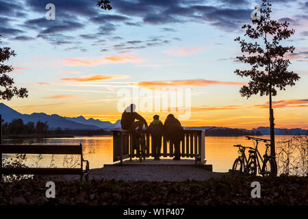 Gruppe Junger Radfahrer im letzten Abendlicht auf der Aussichtsplattform am Chiemsee im Feld Stockfoto