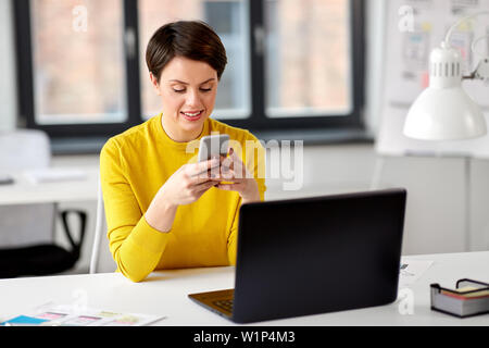 Lächelnd UI-Designer über Smartphone im Büro Stockfoto