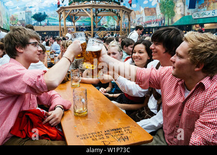 Nachtschwärmer heben ihre bierkrüge mit Toast auf dem Oktoberfest, München, Bayern, Deutschland Stockfoto